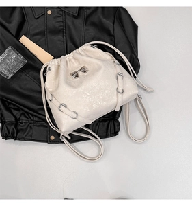 Detail of cream drawstring bucket bag showing silver bow and crackled leather texture