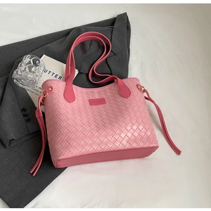 Detail of pink woven tote bag with fringe accents and refined leather texture