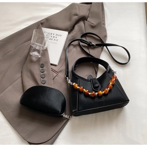 Detail of black pleated PU handbag with amber bead chain and matching mini pouch
