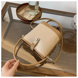 Detail of contrast color bucket bag with silver metal buckle on a glass table
