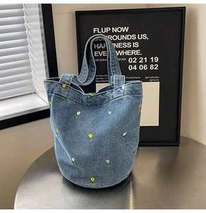 Detail der Stickerei auf blauer Denim-Beuteltasche mit gelbem Blumenstickmuster