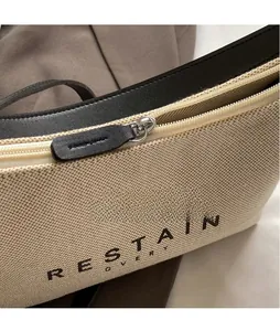 Gros plan sur la fermeture éclair en métal et la tirette en cuir du sac en toile