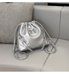 Detail of silver drawstring bucket bag with metallic bow and adjustable chain straps