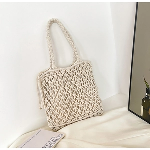 Detailed view of handmade macrame weave and decorative long side tassels on the beige tote