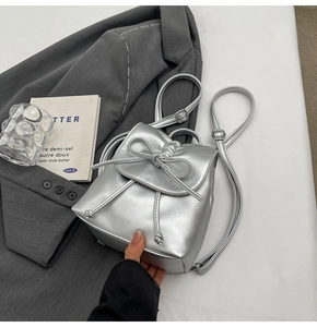 Détail d'un mini sac à dos argenté plissé avec finition métallique et nœud