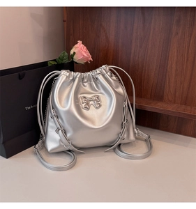 Detailed view of silver drawstring bucket bag with metallic bow and chain strap