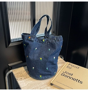 Nahaufnahme der Blumenstickerei auf einer dunklen Denim-Beuteltasche mit Tulpenmotiv