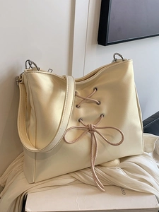 Cream ballet-style leather shoulder bag with large bow and cross-lace detail