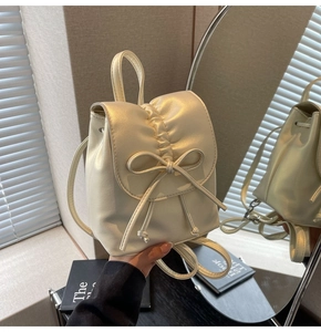 Vue détaillée du mini sac à dos crème avec nœud plissé et finition satinée miroir