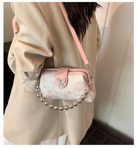 Detail of silver butterfly buckle on pink floral embroidery shoulder bag with bead handle