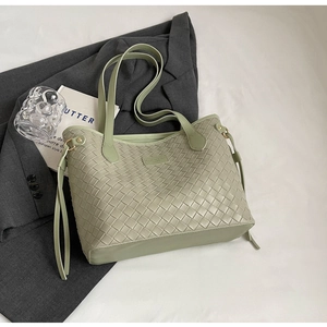 Macro detail of the green woven leather texture and elegant strap on this tote bag