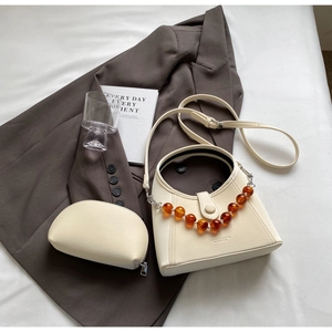 Detail of cream leather handbag set with amber bead handle and matching mini pouch