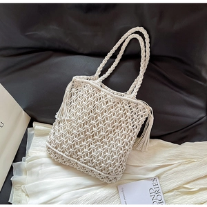 Detailed macro view of white woven crochet bag with tassel decor and cotton grid texture