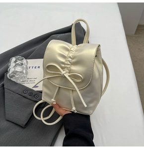 Détail du mini sac à dos crème plissé avec cordon à nœud et finition nacrée en cuir PU