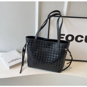 Detail of black woven tote bag featuring gold hardware and stylish leather tassel accents