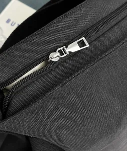 Nahaufnahme des silbernen Reißverschlusses und der Textur der schwarzen Canvas-Tasche