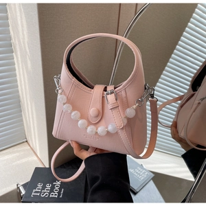 Detail of pink beaded handbag featuring a rounded handle and frosted decorative beads