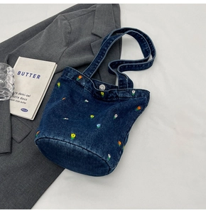 Detailansicht der Blumenstickerei auf der tiefblauen Denim-Beuteltasche mit rundem Boden