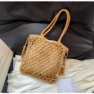 Detail of the woven tote bag showing fringe accents and the white drawstring inner pouch