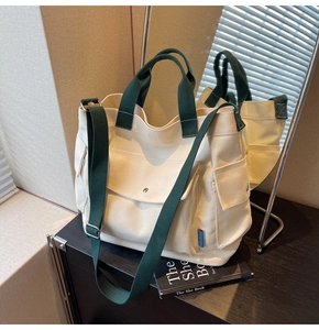 Detail of cream canvas tote bag with green straps and adjustable shoulder strap