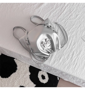 Detailed view of silver metallic drawstring backpack with 3D bow and sleek chain straps
