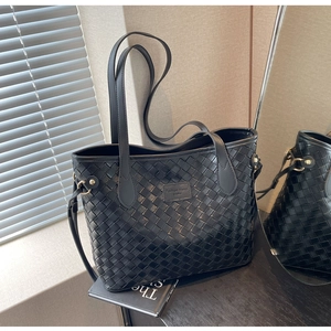 Close-up of black woven leather tote bag with elegant handles and metal hardware detail
