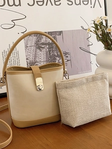 Minimalist bucket bag in cream and tan leather featuring a metal lock and inner pouch