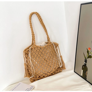 Detailed view of bohemian hollow knit straw bag with drawstring liner and side tassels