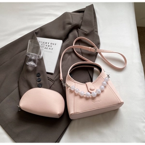 Pink crossbody bag detail with pearl handle and matching cosmetic pouch set