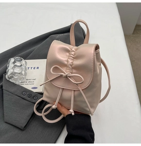Détail d'un mini sac à dos rose nacré avec texture plissée et nœud de décoration