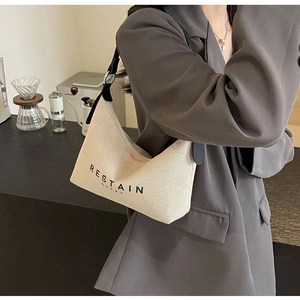 Vue détaillée du sac hobo tissé beige avec logo RESTAIN et bandoulière noire