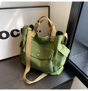 Detail view of army green canvas tote bag showing functional side pockets and strap texture