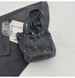 Detailansicht der dunkelgrauen Jeans-Beuteltasche mit bunten Blumen-Stickereien und Magnetverschluss