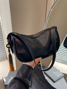 Chic black underarm shoulder bag with elegant tassel and subtle textured faux leather