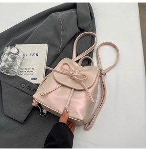 Détail d'un mini sac à dos rose nacré plissé avec nœud décoratif et cordon de serrage