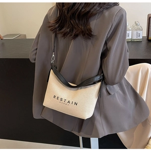 Détail du sac dumpling en toile beige avec bordures en cuir noir et bandoulière chic