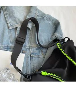 Detail of black nylon crossbody bag featuring neon green woven rope and adjustable strap
