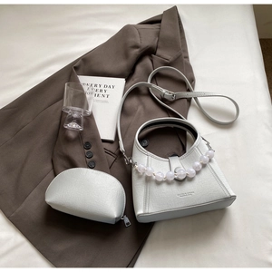 Detail of white textured leather handbag with pearl chain and matching small coin purse