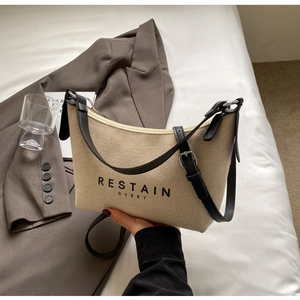 Détail du sac beige en toile avec bordure en cuir noir et impression de lettres