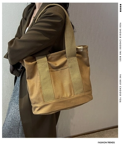 Detail view of khaki canvas tote bag with reinforced handles and functional outer pocket