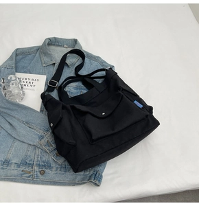 Detailed top view of black canvas tote bag with multi-pockets on denim jacket background