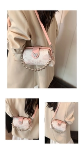 Close-up of pink butterfly buckle and silver ball handle on embroidered shoulder bag