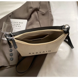 Détail du sac bandoulière en toile avec anneaux métalliques et bandoulière en cuir