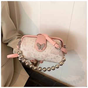 Detail view of floral embroidery and silver butterfly buckle on crossbody handbag