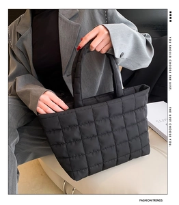 Detail of black quilted tote bag with soft padded texture and minimalist handle design