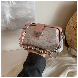 Close-up of intricate butterfly metal buckle and star embroidery on pink leather bag