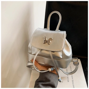Detailansicht des silbernen Metallic-Rucksacks mit dekorativer Schmetterlingsschnalle