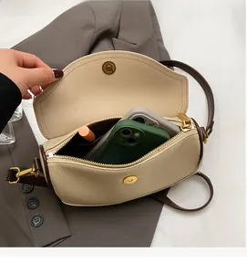 Detail view of beige pebbled leather saddle bag showing interior space for phone and lipstick