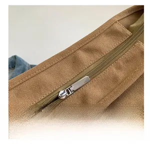 Detailed close-up of a smooth silver metal zipper on a khaki canvas tote bag