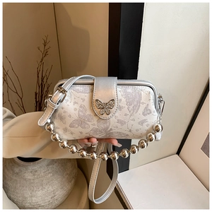 Detail of silver embroidery handbag featuring butterfly lock and metallic bead chain strap